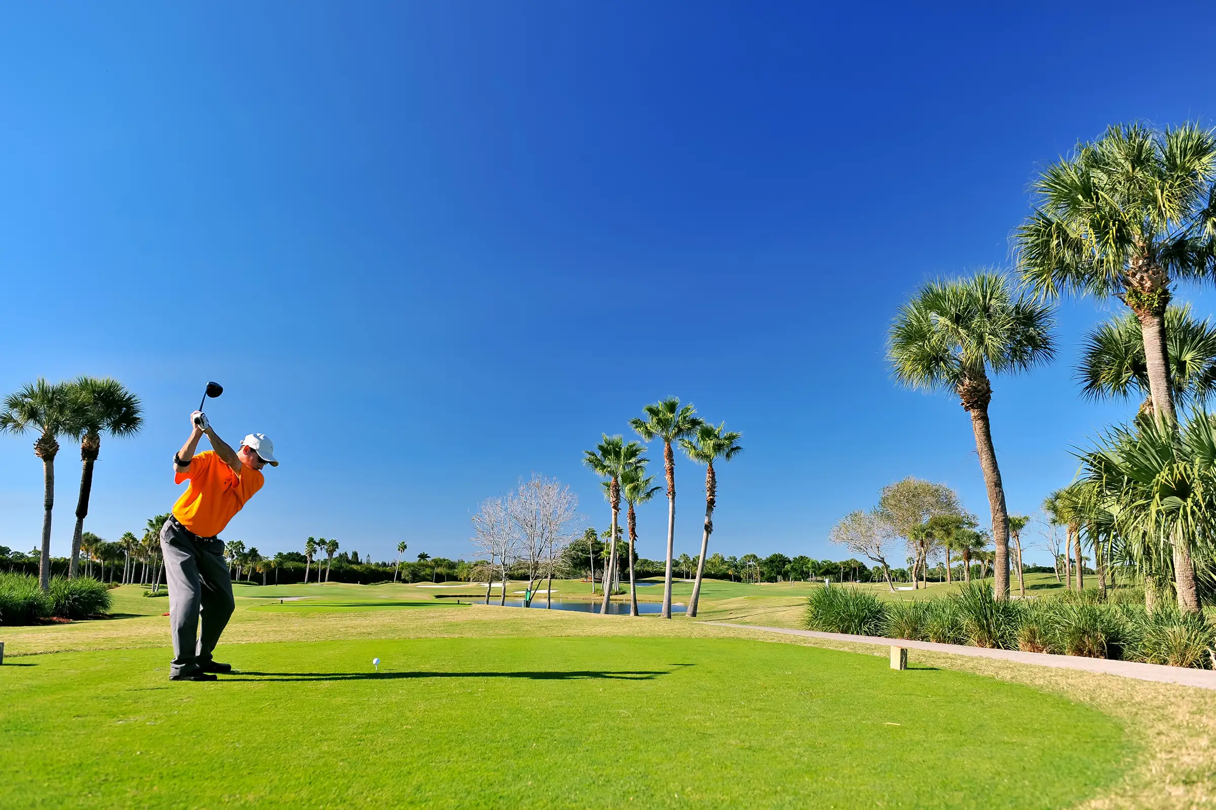 Golfer teeing off under clear Florida skies at River Hall