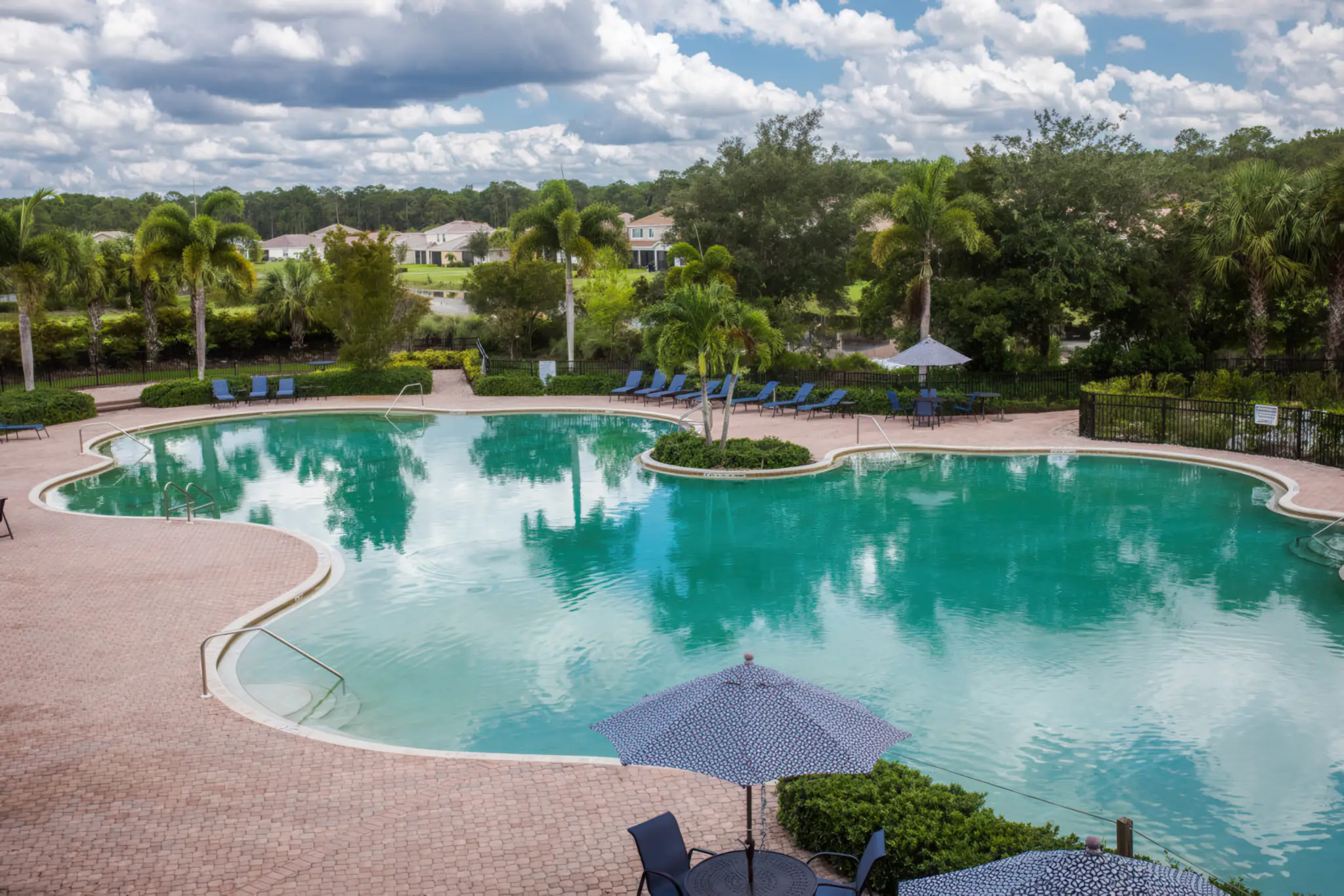 Lagoon-style resort pool with lounge chairs and palms at Hampton Lakes in Alva FL